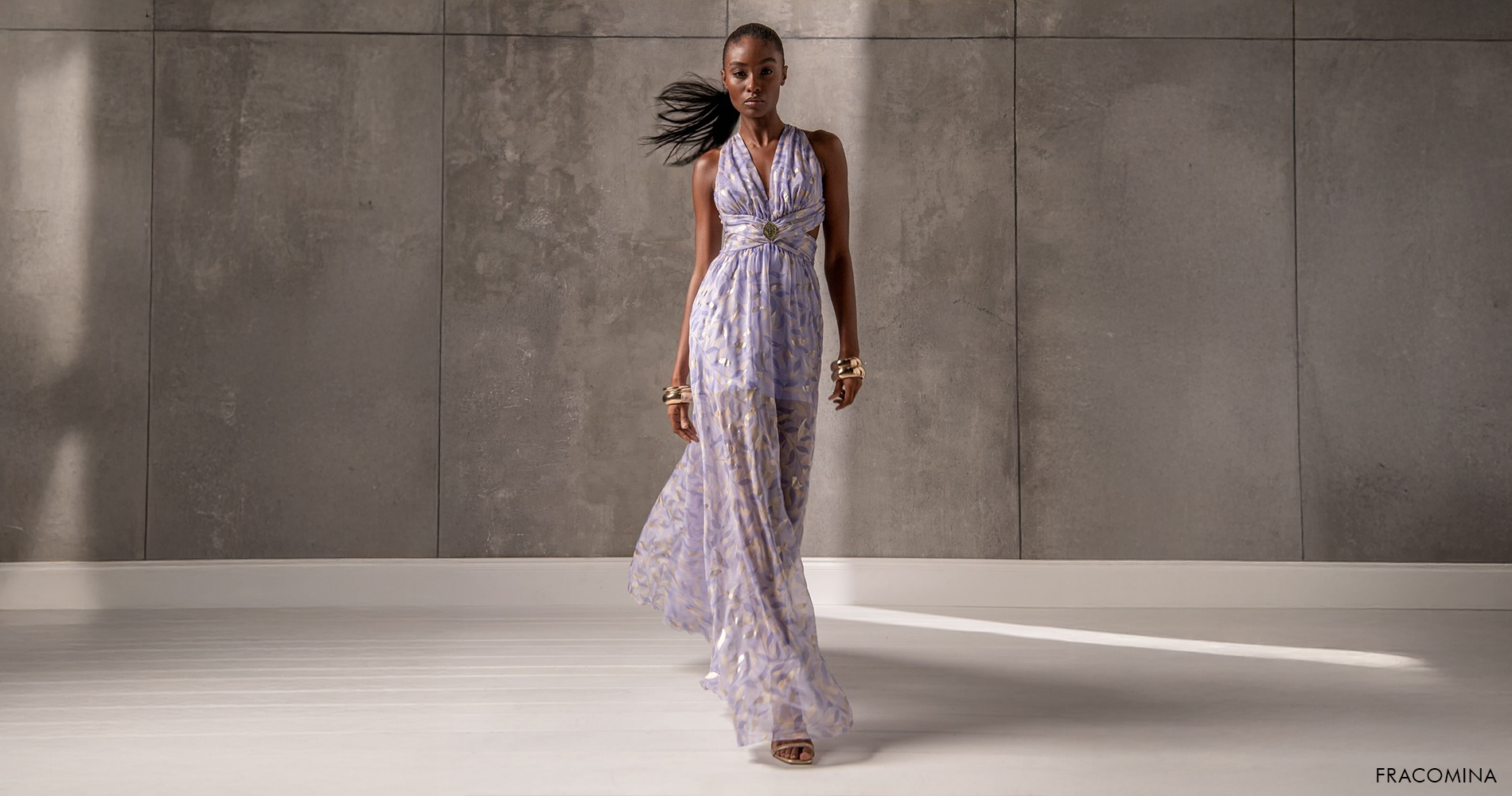 Ženska v elegantni vijolični maturantski obleki s subtilnim vzorcem in poudarkom v pasu.