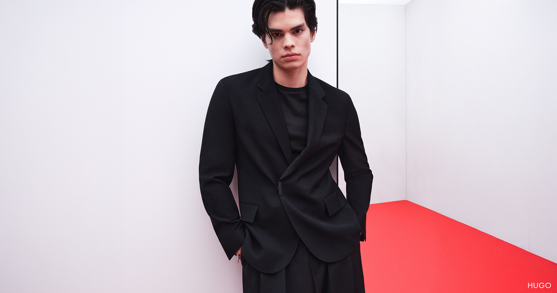 Eleganten moški v črni obleki z modernim, minimalističnim ozadjem.