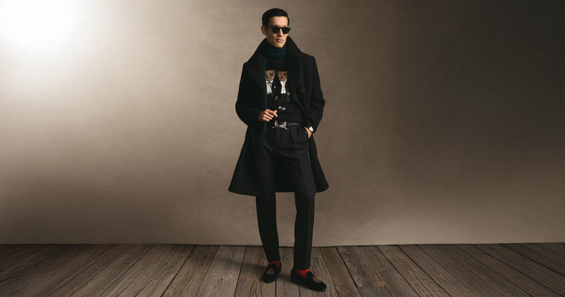 Moški v pletenini z motivom Ralph Lauren medvedka v kombinaciji z elegantnim plaščem.