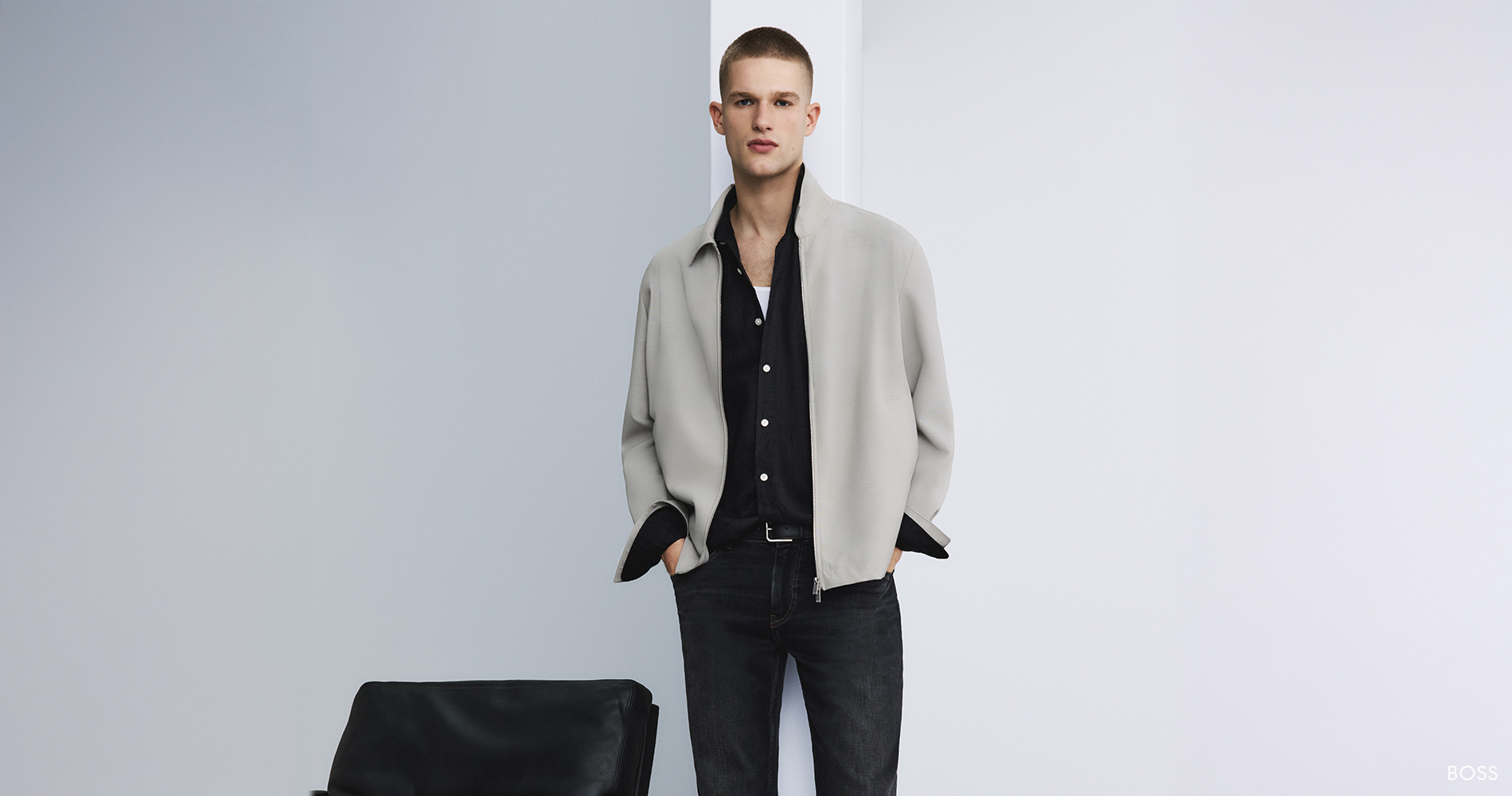 Moški poslovno-casual videz z minimalistično jakno, črno srajco, temnim džinsom in loaferji – sodobna eleganca za službo in vsak dan.