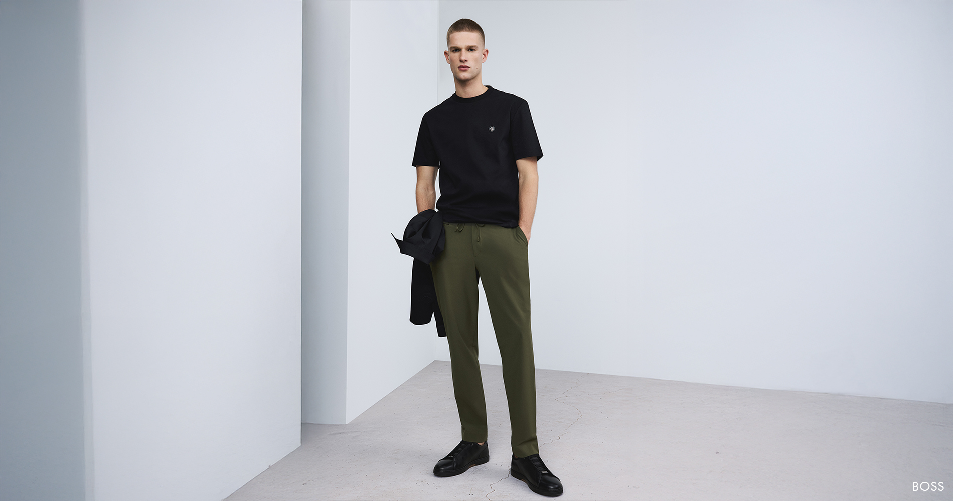 Moški casual videz s črno premium majico in olivno zelenimi hlačami združuje udobje, minimalistični slog in brezčasno eleganco.
