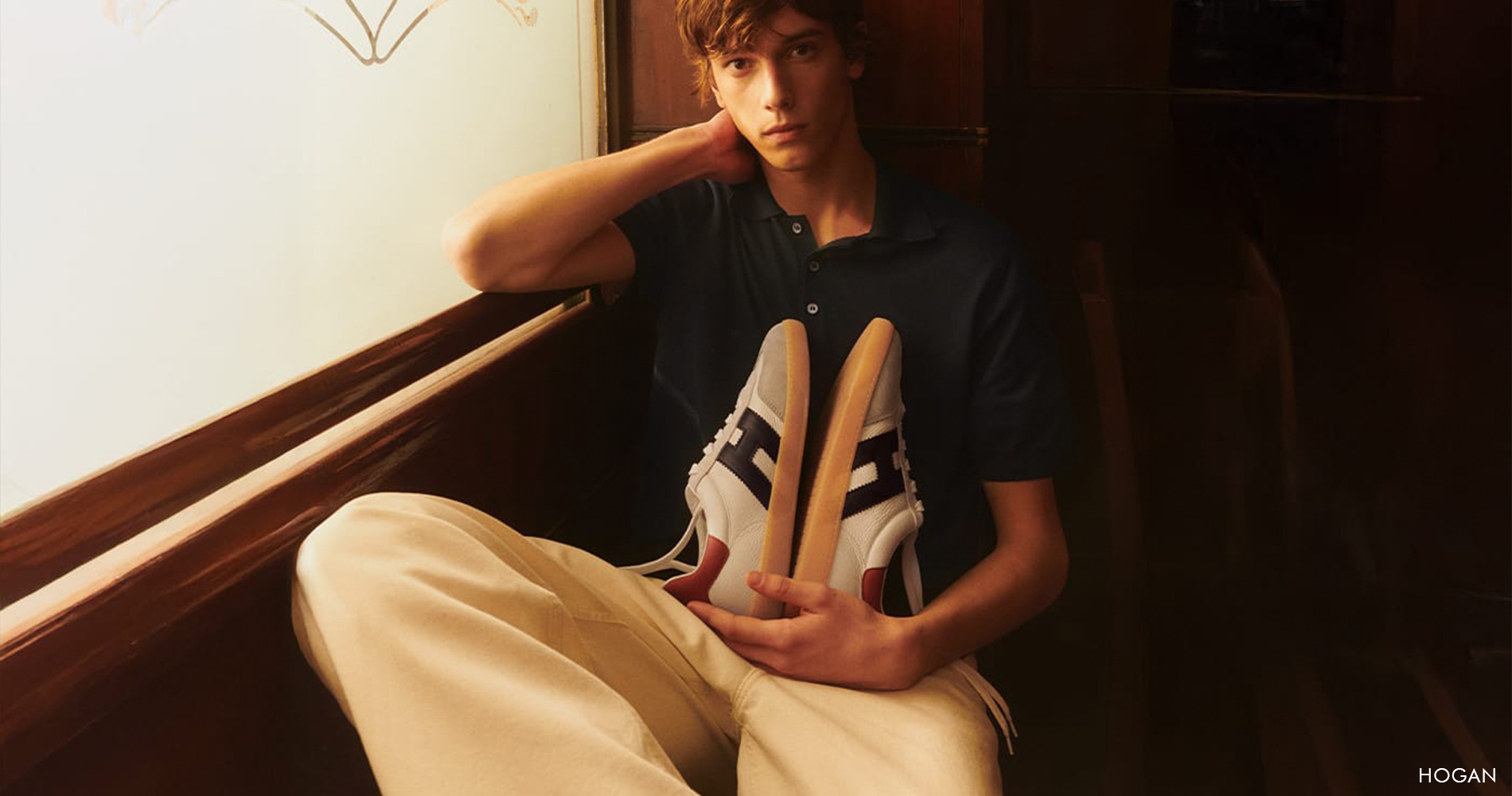 Mlad moški v modni majici s supergami v roki.