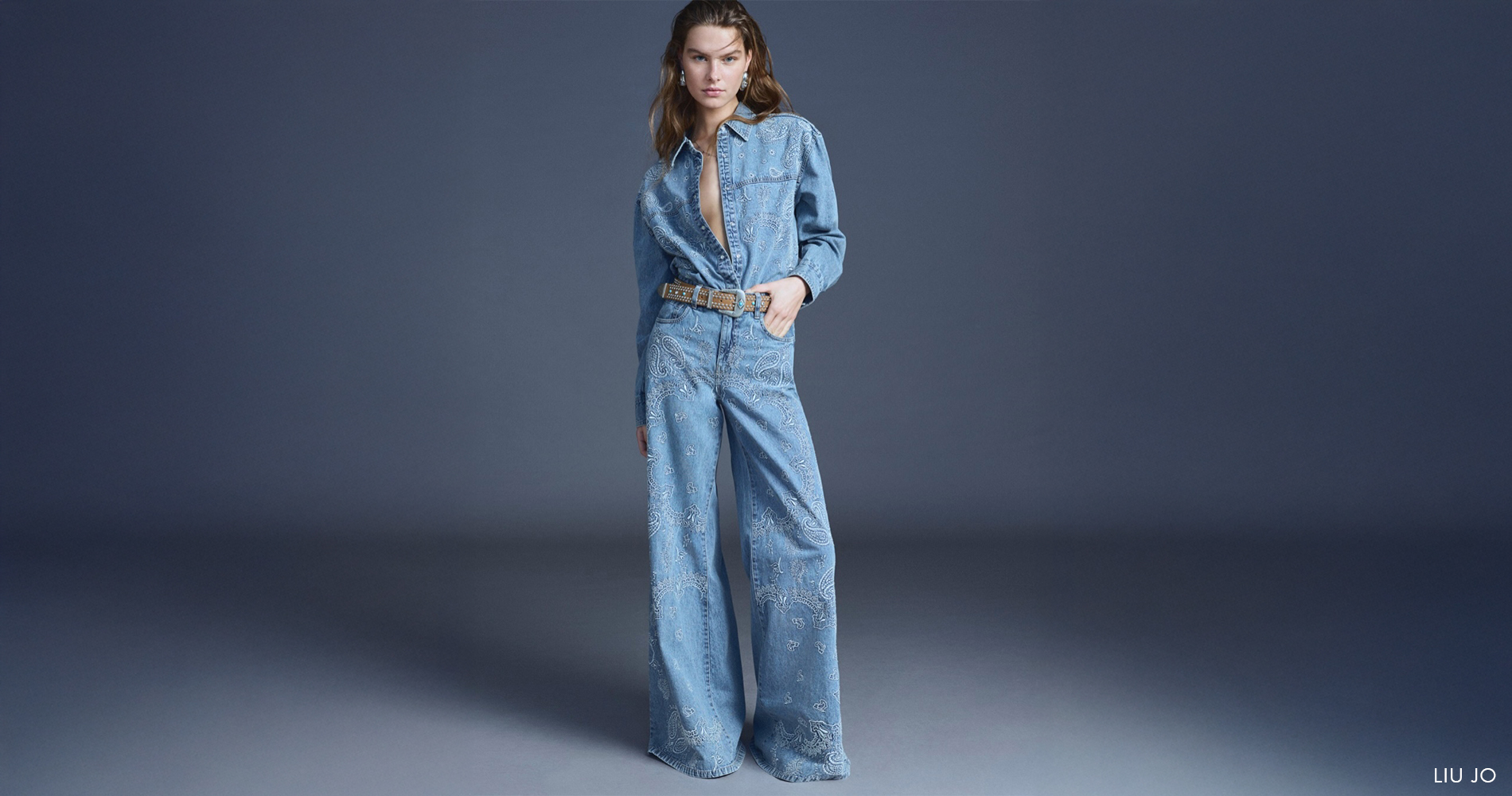 Trendovsko oblečena ženska v jeans hlačah in denim srajci z vezeninami.