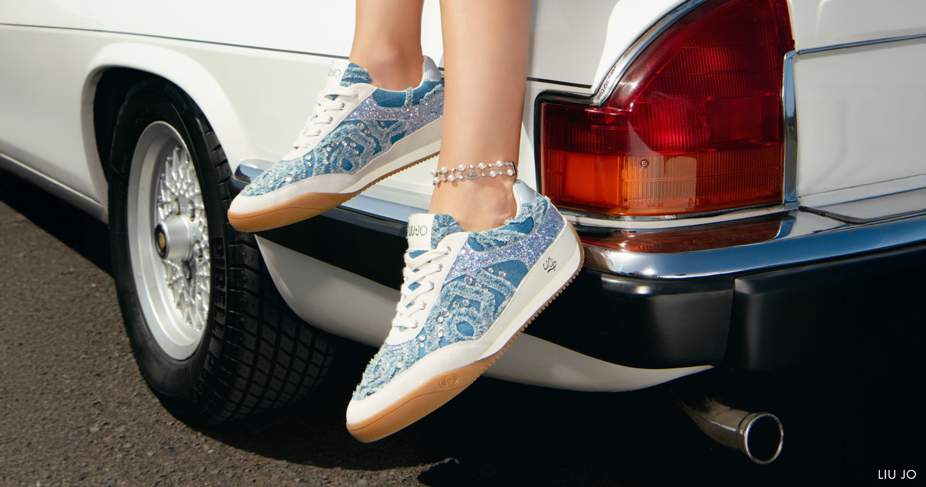 Slika ženske na avtomobilu, vidne so superge iz denima, jeans krilo in jeans jakna.
