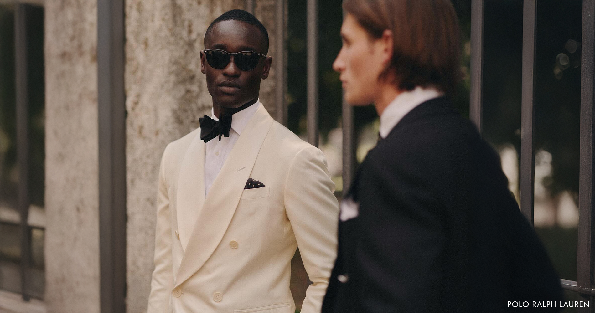 Two elegantly dressed men in white and black tuxedos.