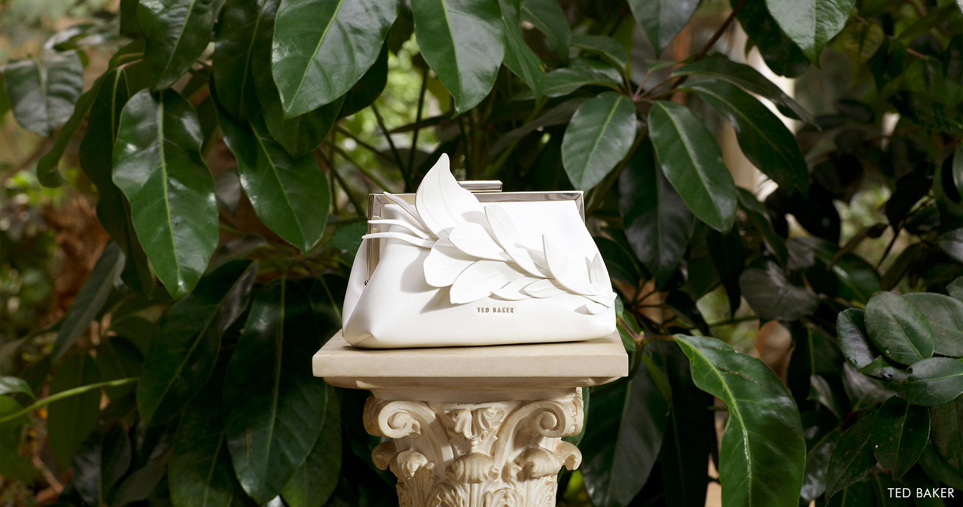 An elegant white handbag on a Greek-style pedestal.