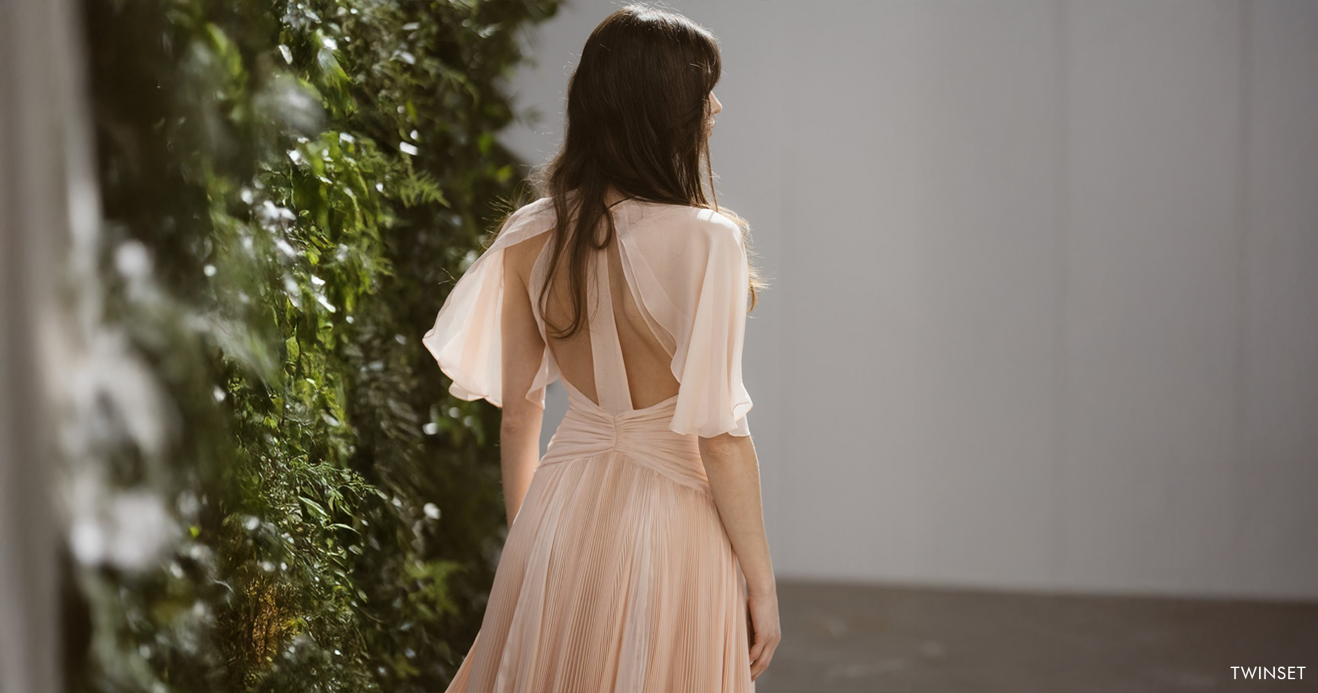An elegant powder pink pleated dress with an open back and airy sleeves.