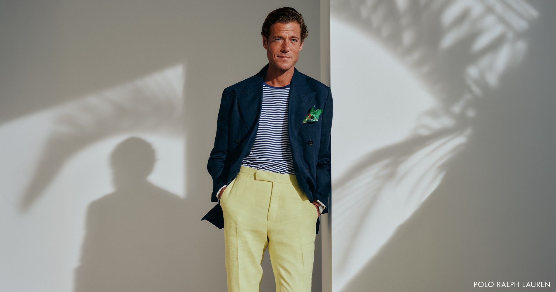 Uglajen mo&scaron;ki ležerno sloni ob steni, vidna je senca palme, kar ustvarja poletno tropsko okolje.