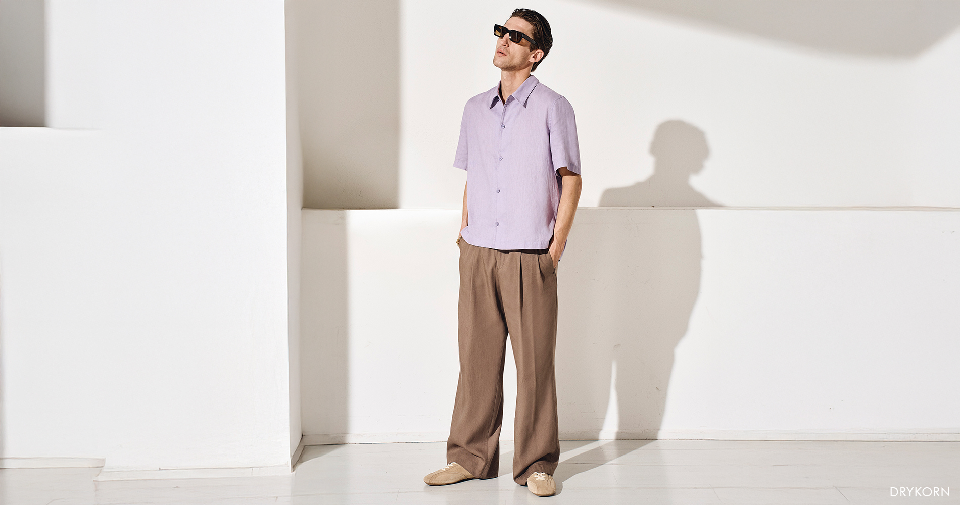 Discover a relaxed men’s spring style with a lightweight purple shirt, wide beige trousers, and modern details for an elegant, comfortable everyday look.