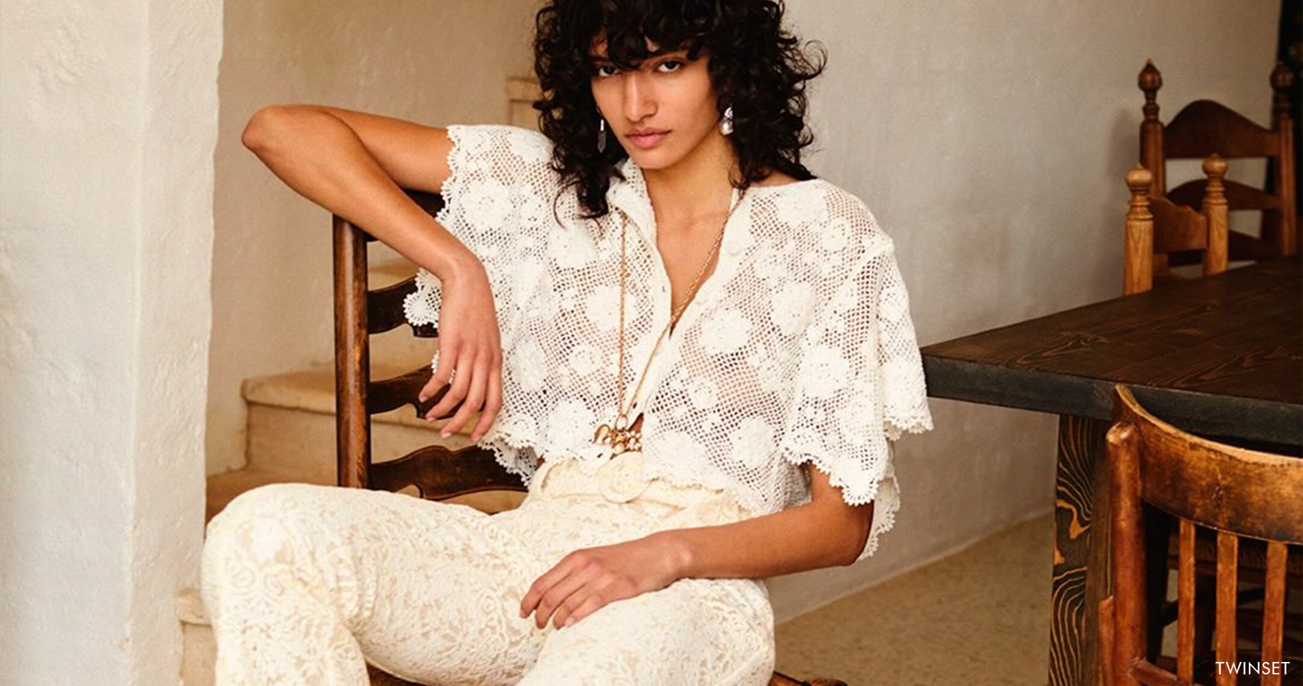 A romantic woman in a vintage setting, wearing a lace blouse and lace trousers.